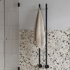 En vägg i ett badrum. På väggen hänger två avlånga svarta handdukstorkar.