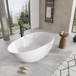 Ett barum med ett fristående vit badkar stående i mitten. Framför badkaret är ett bad gråa tofflor placerade.